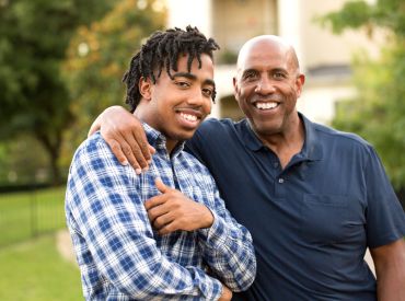 Middle-aged father with arm around young adult man
