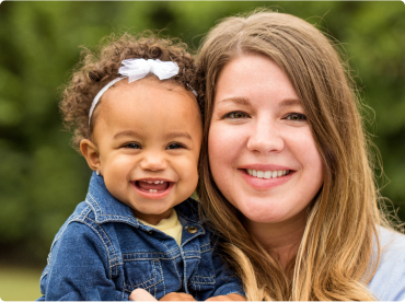 Mom and toddler daughter smiling at camera