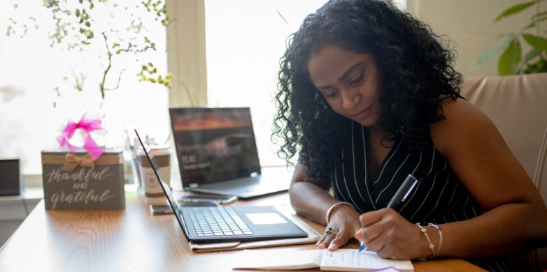 woman sitting at desk writing in notebook