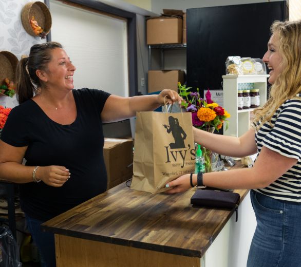 Pregnant worker handing a bag to a customer