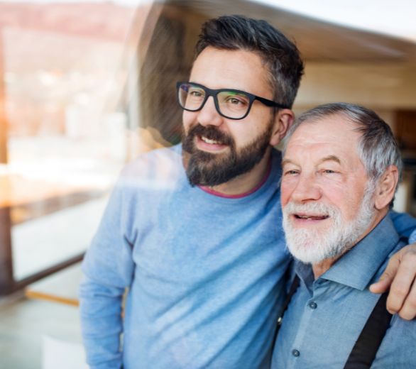 Man with his arm around an older gentleman