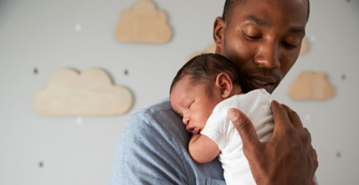 Dad holding sleeping newborn baby on his shoulder