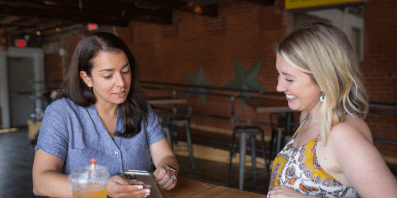 Woman showing her friend something on her cell phone