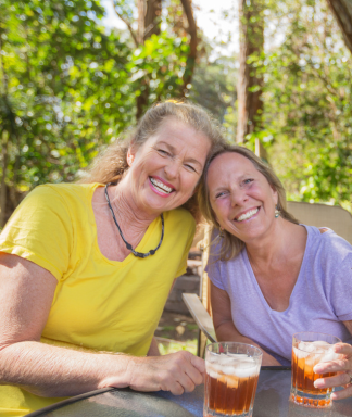 Two smiling middle-aged women with their heads tilted together