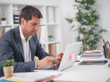 Man in a suit typing on laptop