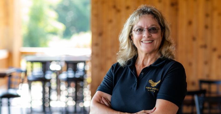 Woman in winery with arms crossed smiling at the camera