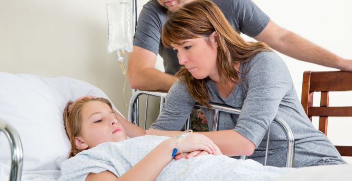 Parents next to their daughter in a hospital bed