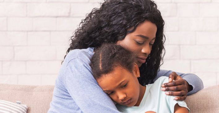 Woman sitting on a couch comforting her daughter