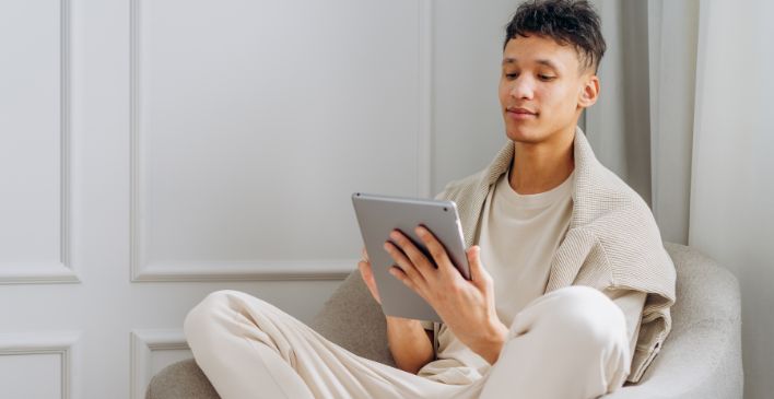 Young man sitting in an armchair looking at a tablet