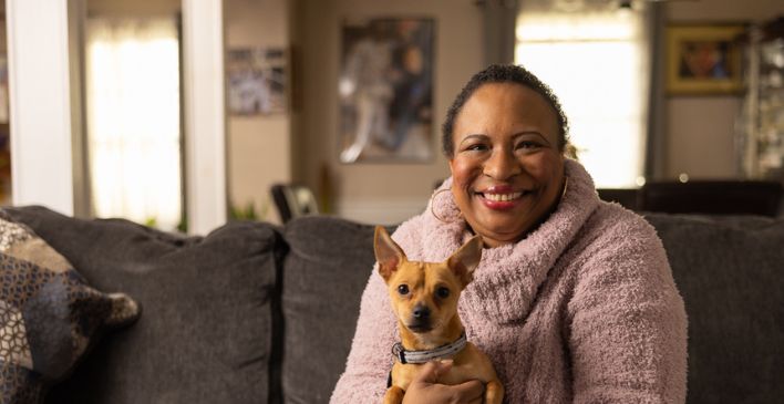 Woman sitting on couch holding small dog