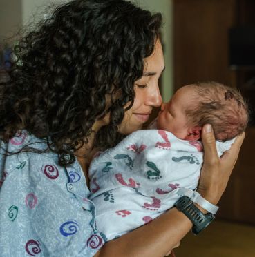 woman in a hospital gown with a newborn baby